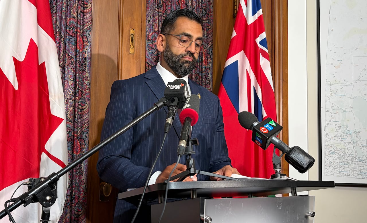 A man in a suit speaks at a podium.