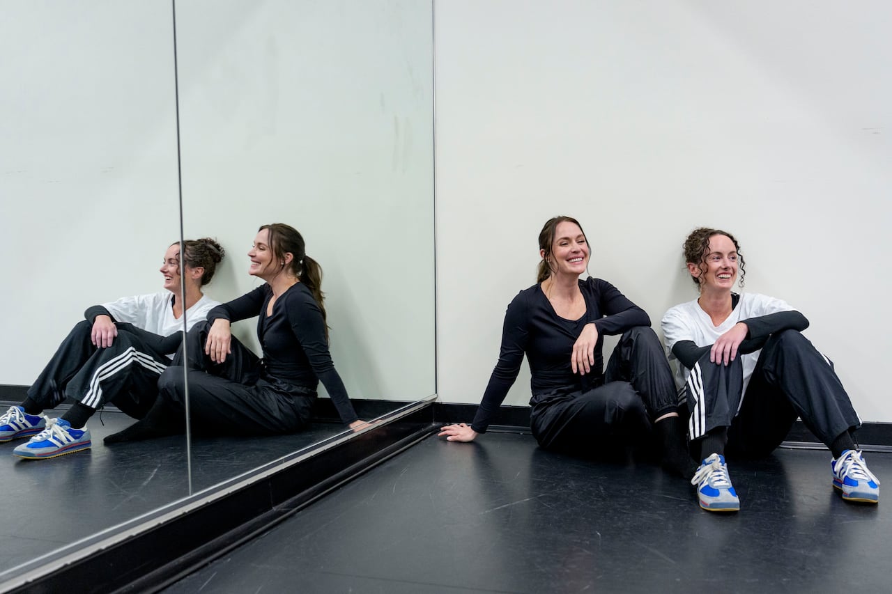 Two women sit next to each other with their reflections in the mirror.