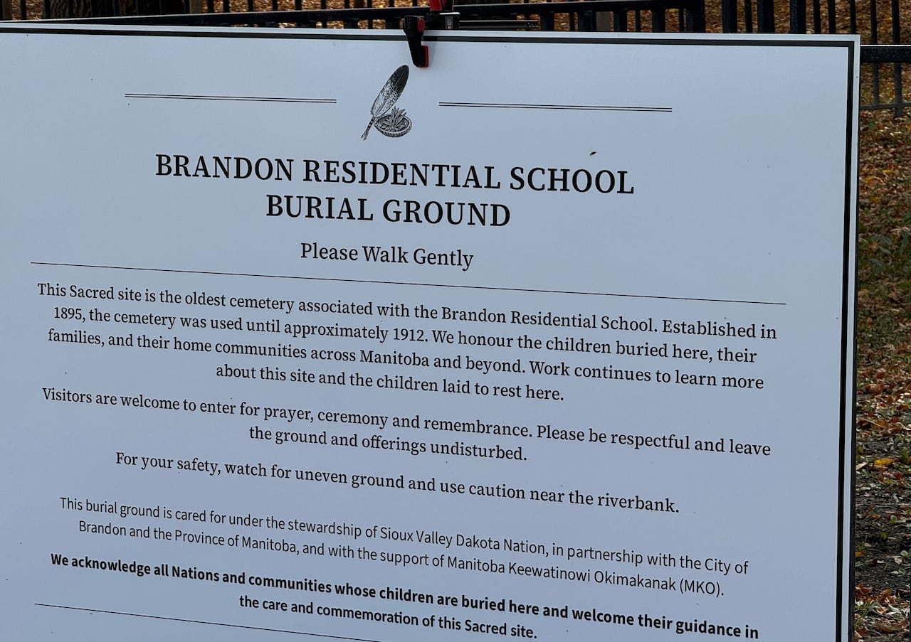 A sign with text that includes "Brandon Residential School Burial Ground -- Please Walk Gently."