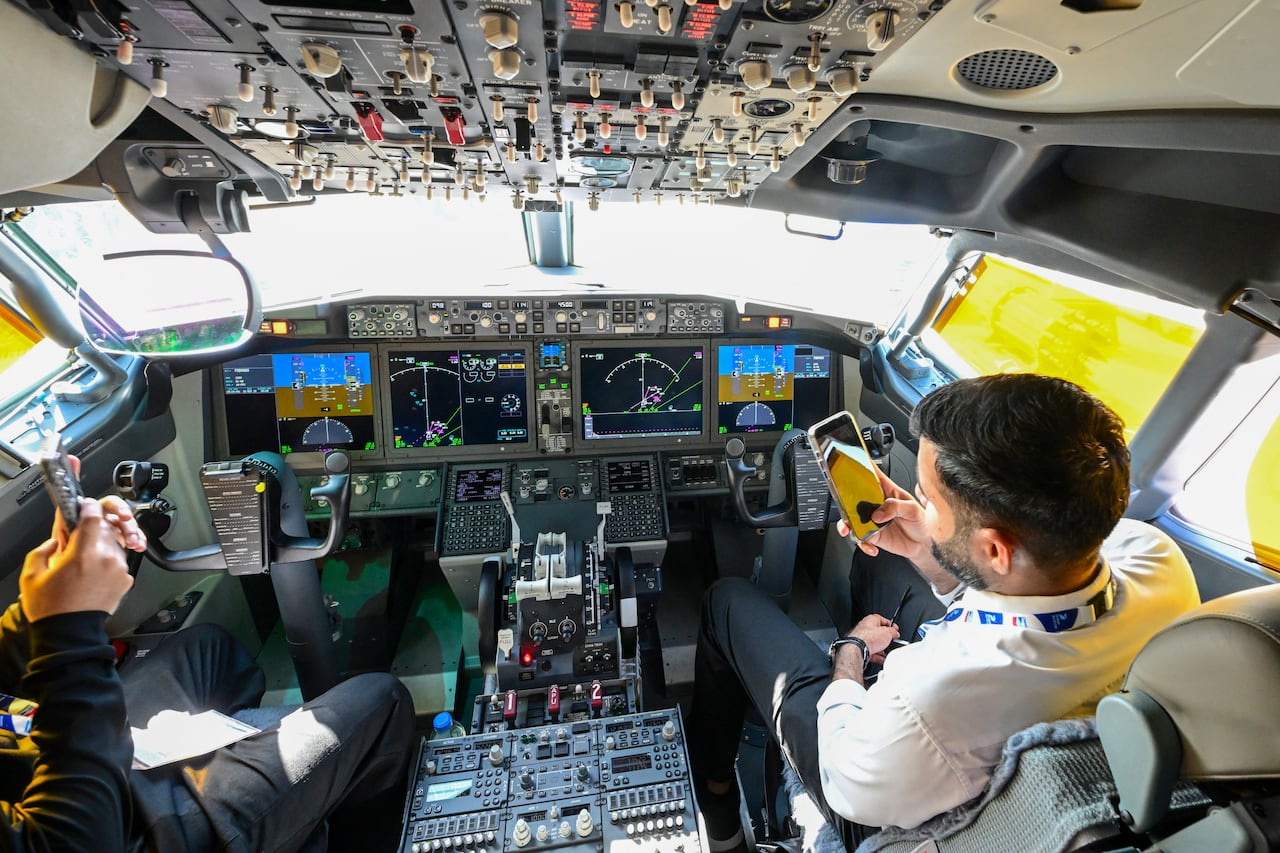 Two people are shown inside the cockpit of an airplane.