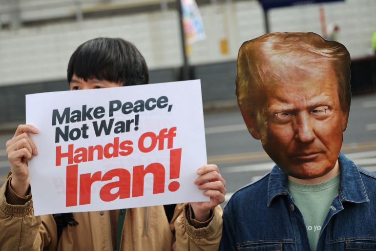 An activist wearing a cutout mask of Trump attends a rally to condemn the US-Israel war on Iran, with others in front of the US embassy in Seoul, South Korea, March 1, 2026