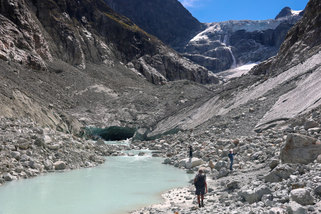 Hikers walk on the moraine at the Mont Mine glacier near Evolene