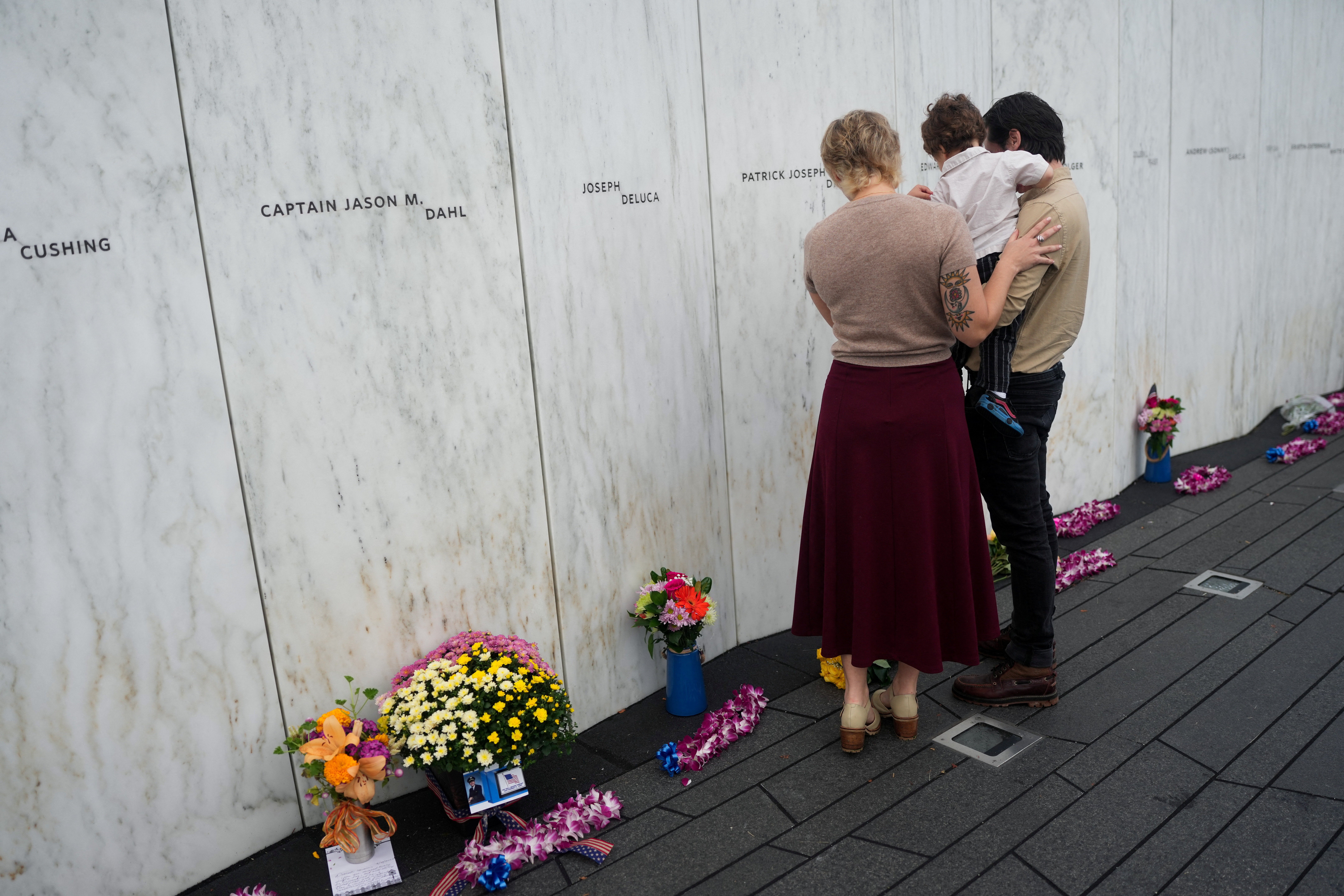 Ryan Gould, grandson of Flight 93 victim Patrick Joseph Driscoll, stands next to the Wall of Names with his wife and son, at the Flight 93 National Memorial, where mourners gathered to recognize the 25th anniversary of 9/11 and the passengers who fought against hijackers to divert the plane away from the nation’s capital