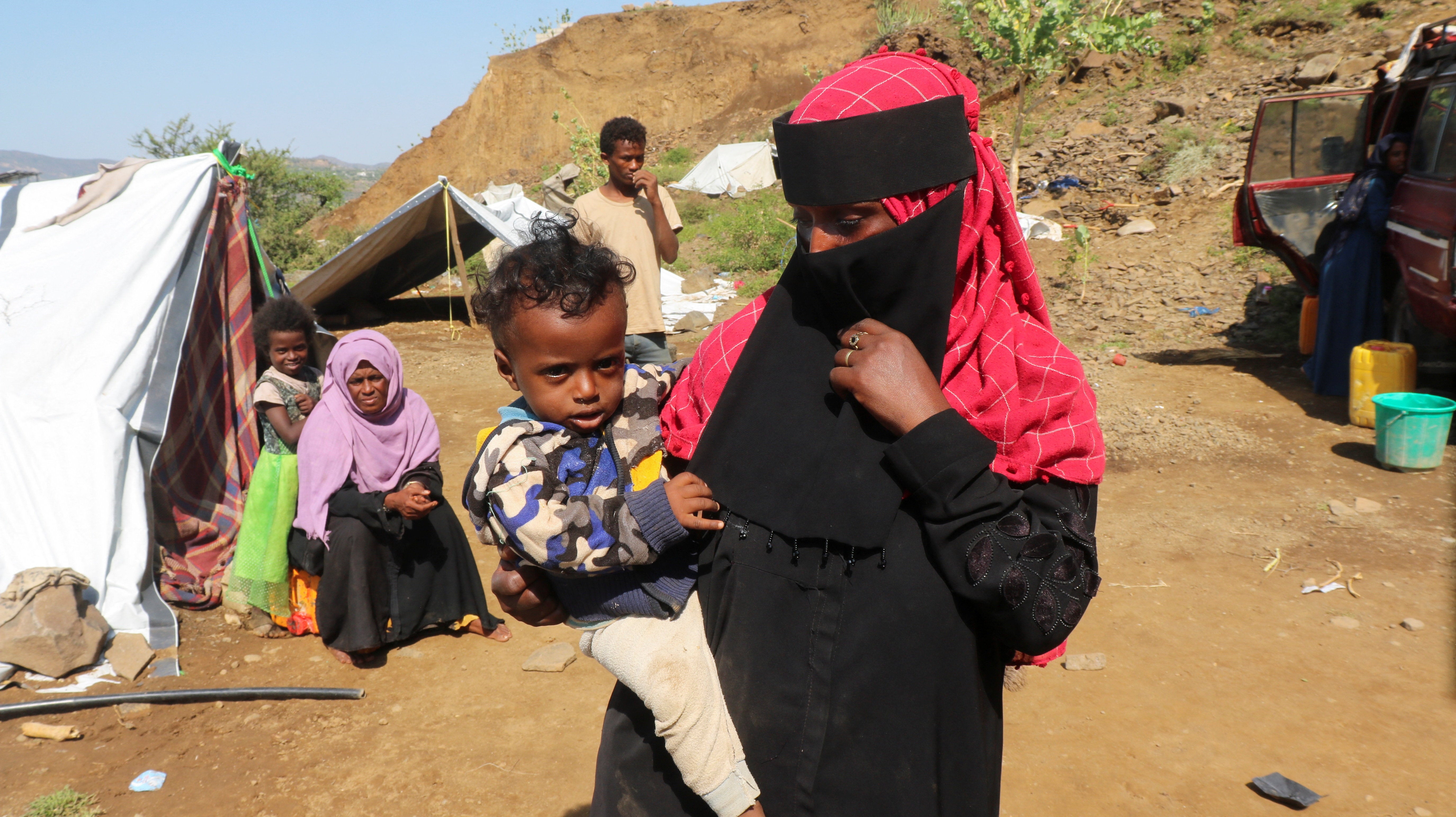 A displaced woman holds a child at a makeshift camp for people displaced by clashes between Iran-aligned Houthi fighters and Saudi-backed Yemeni government forces, in Taiz province, Yemen September 21, 2026