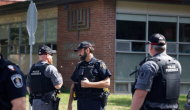 Police investigators speak in front of Sons of Jacob Synagogue, where a police officer was shot outside a Yom Kippur gathe...