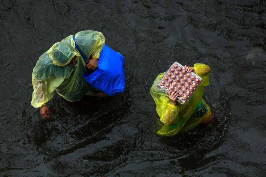 People carry food as they wade through floodwaters during rain in Bangkok, Thailand, on Saturday.