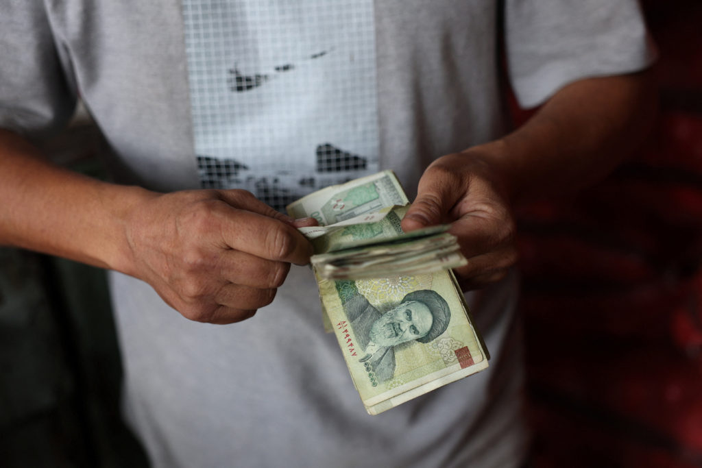 A shopkeeper holds Iranian rials at a local market in Tehran