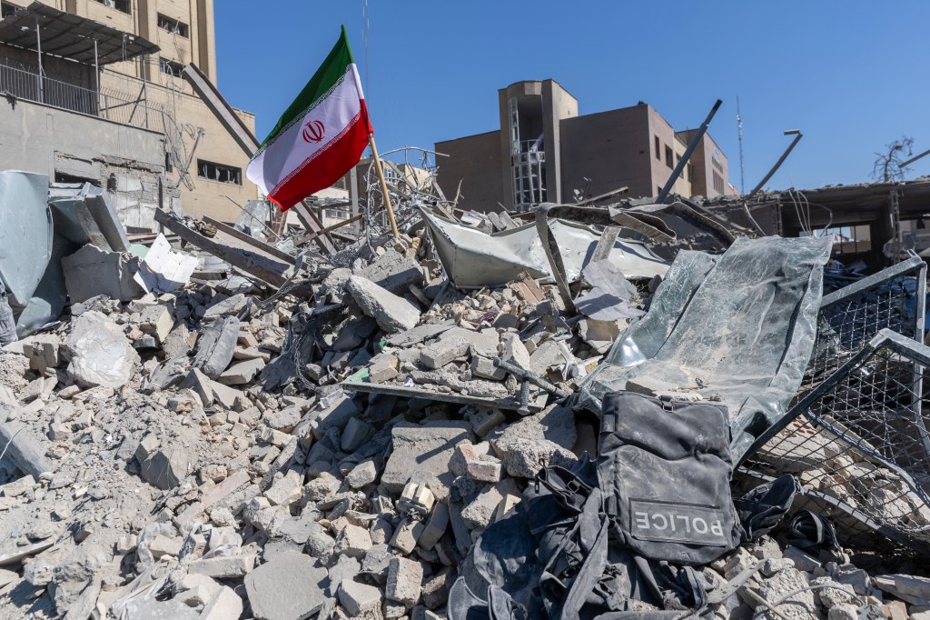 Iranian flag planted in the rubble of a police station in Tehran after airstrikes.