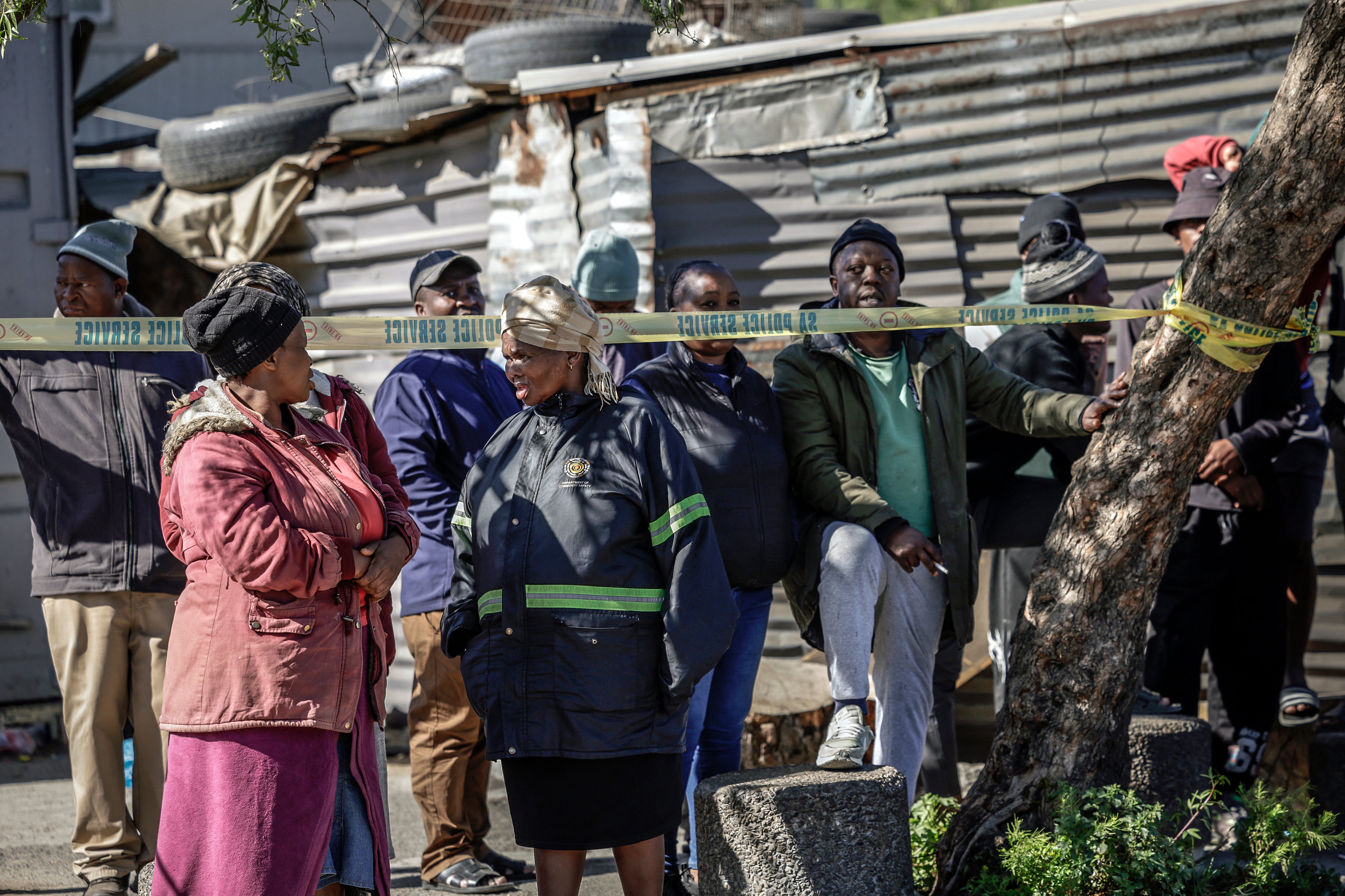 Bystanders look on behind police tape near an entertainment venue in Somerset West on September 27, 2026, after gunmen stormed the premises
