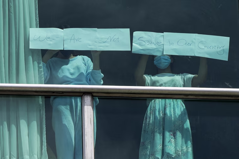 Migrants deported from the US place papers with a written message in the window that reads: "We are not save in our country."
