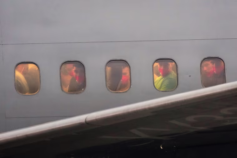 A group of men appear to be looking out of an airplane's windows.