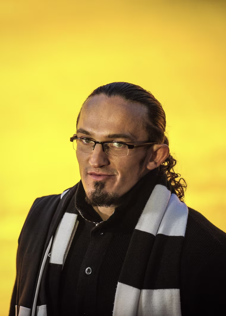 Adrian Neville in front of a yellow backdrop/