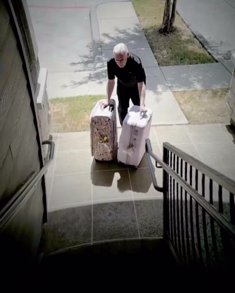 Donald Johnson moving two suitcases near a staircase outside