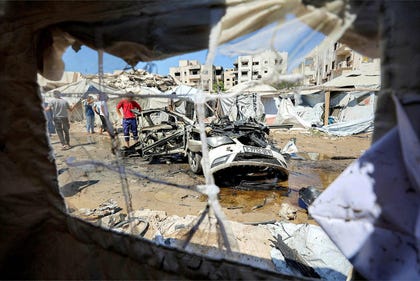 People gather around a destroyed vehicle following an Israeli strike in Gaza City on Tuesday.