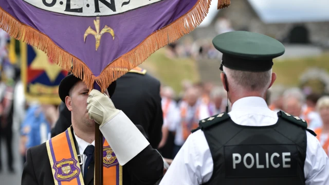 Orangeman holds banner in front of PSNI officer