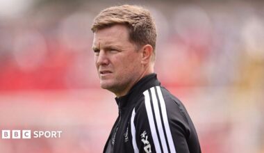 Eddie Howe, wearing a black-and-white tracksuit stop, looks on before a Newcastle match