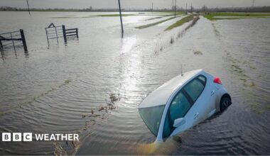 Car partially submerged, surrounded by flooded fields following Storm Chandra