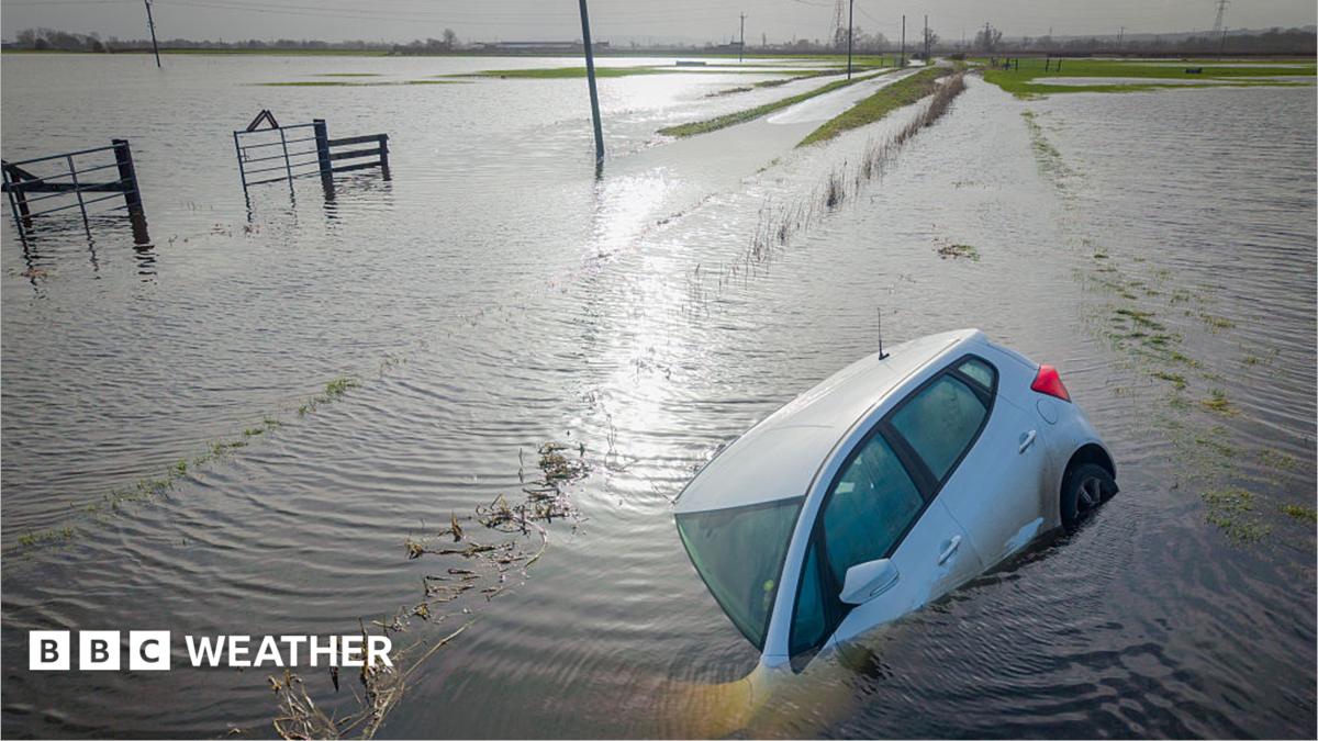 Car partially submerged, surrounded by flooded fields following Storm Chandra