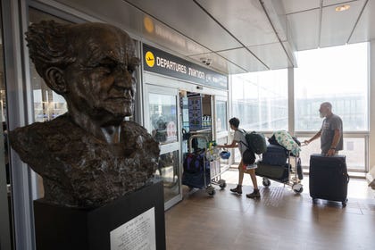 Israelis pushing luggage through Ben-Gurion International Airport, near a bust of the airport's namesake. Credit: Tomer Appelbaum Israelis pushing luggage through Ben-Gurion International Airport, near a bust of the airport's namesake.