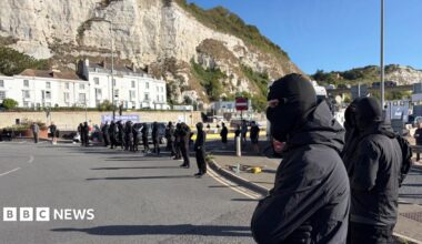 A row of masked men block a road at the entrance to the Port of Dover.