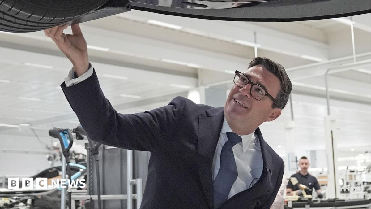 Prime Minister Andy Burnham looks at a car on the production line during a visit