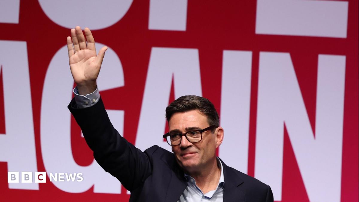 Andy Burnham waves to the audience in Liverpool against a "Hope Again" banner in the background