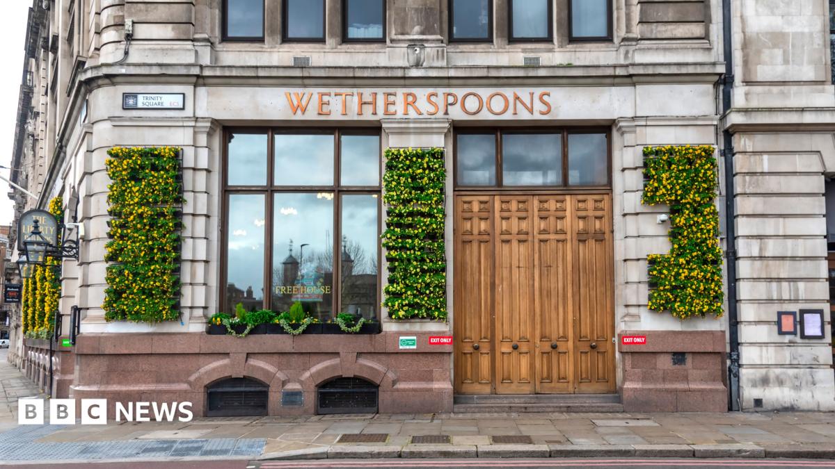 The exterior of a pub with large windows and flowers growing on the walls