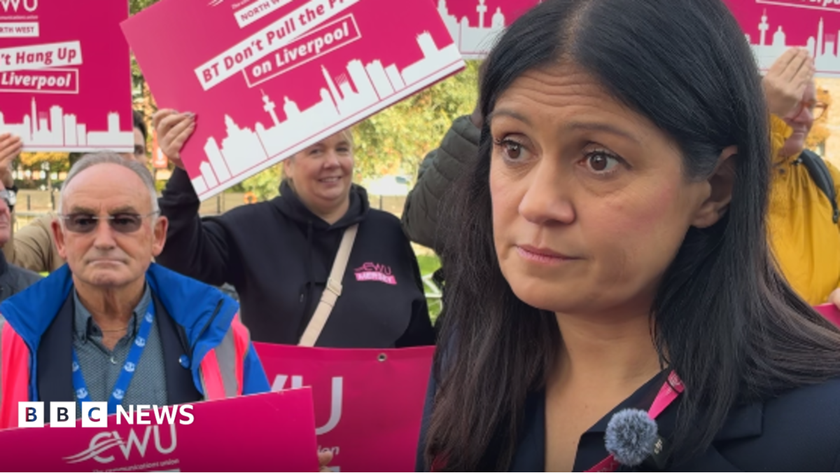 Lisa Nandy MP with long black hair wearing a black jacket stands by CWU members protesting outside the Labour Conference in Liverpool over a plan to relocate jobs from the city.