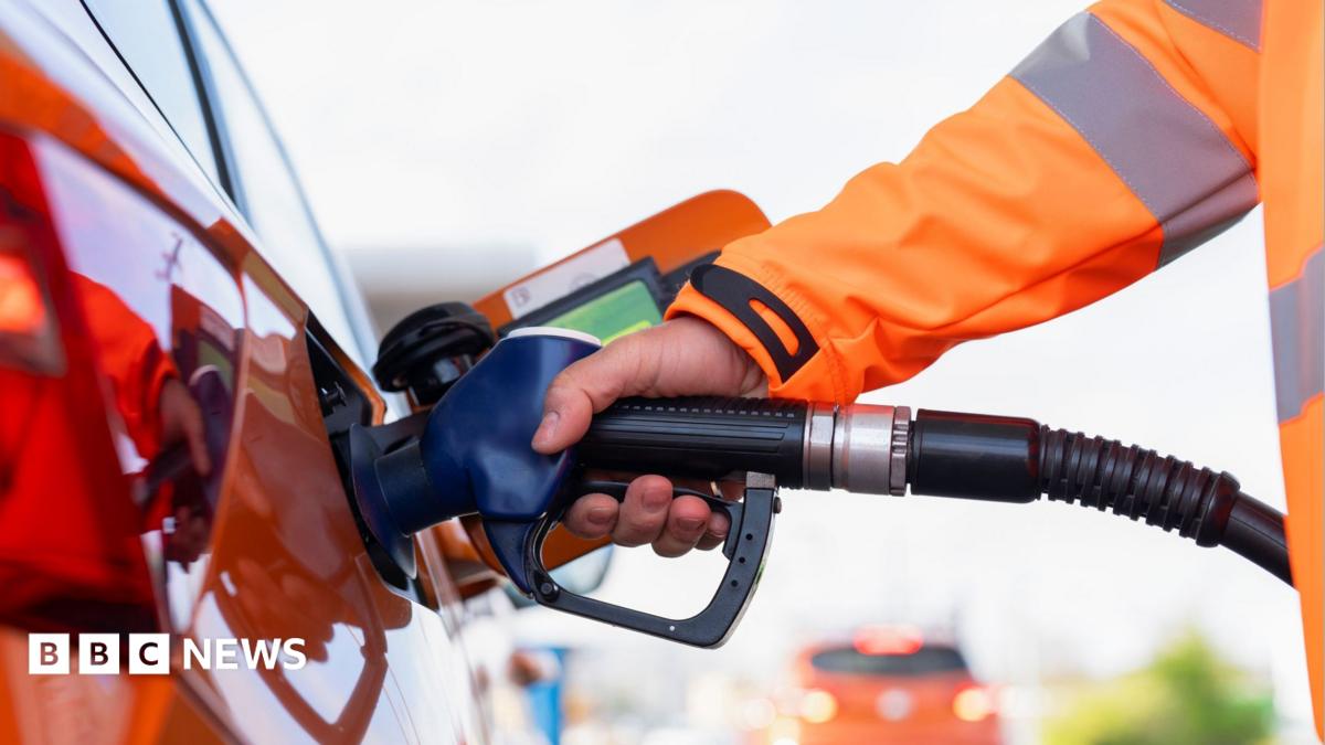 Close-up of a man refuelling orange car at gas fuel station. Male filling diesel at petrol station using a fuel nozzle