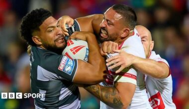 Huddersfield Giants' Taane Milne (left, in black and grey) is tackled by Hull Kingston Rovers' Elliot Minchella (right, in white and red)