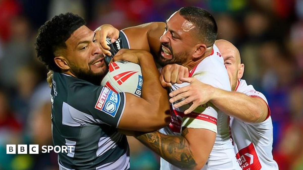 Huddersfield Giants' Taane Milne (left, in black and grey) is tackled by Hull Kingston Rovers' Elliot Minchella (right, in white and red)