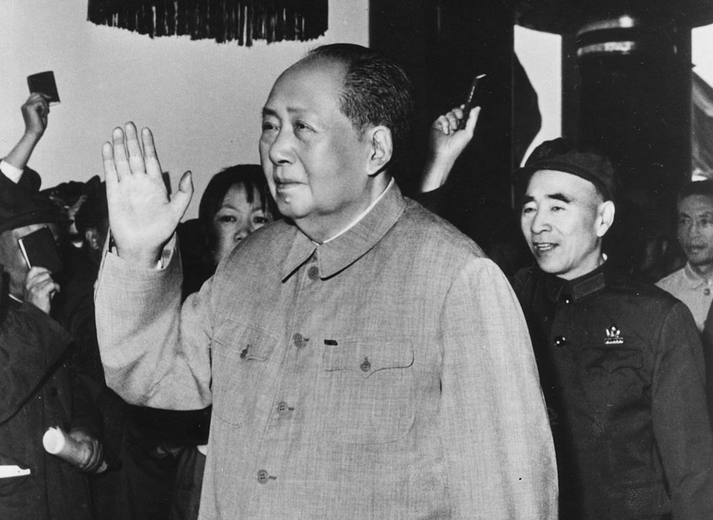 An elder Mao Zedong waves to a crowd.