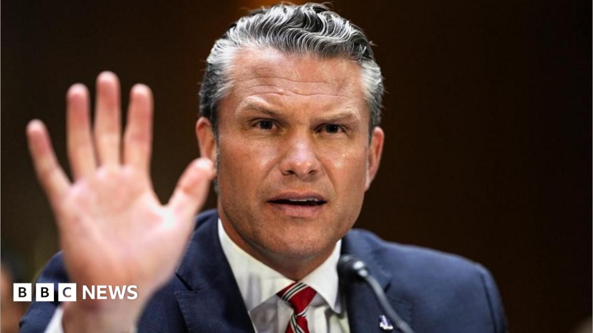 Pete Hegseth gestures by lifting his hand as he frowns