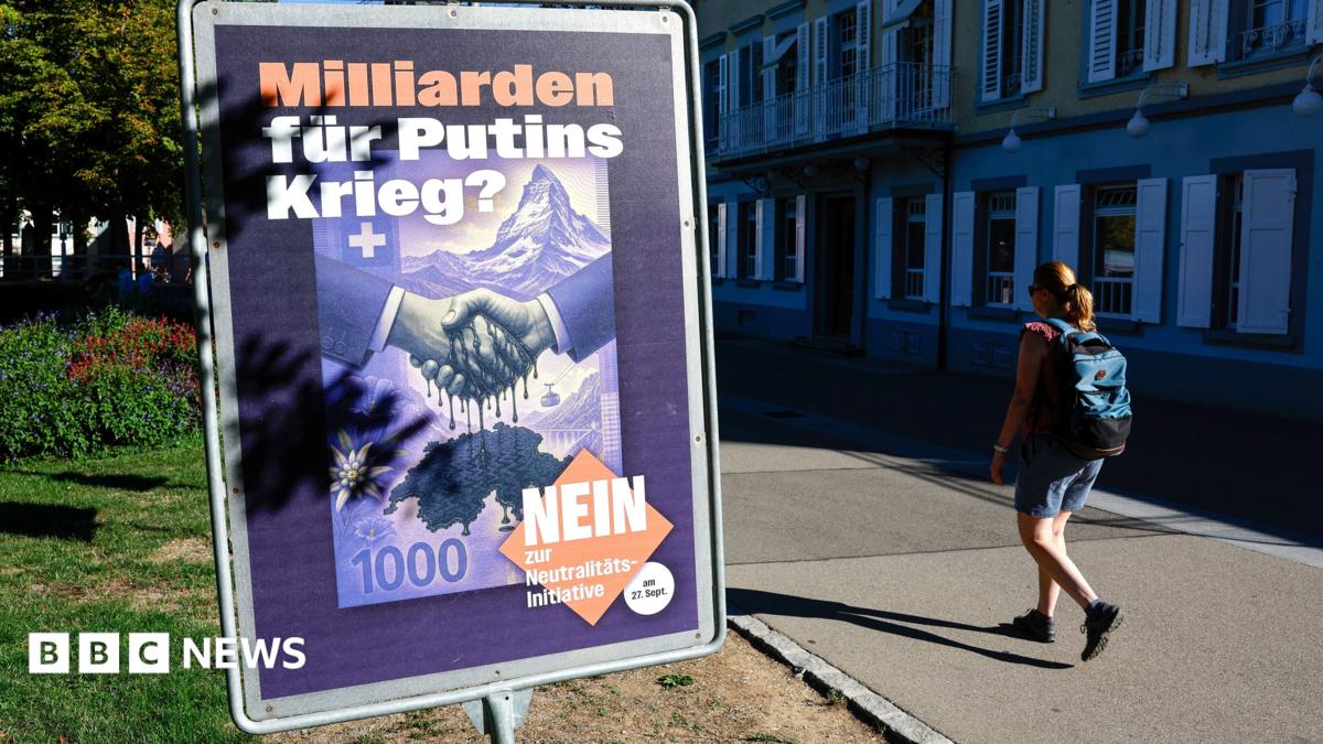 A woman wearing a backpack walks past a placard against the vote on the "Neutrality Initiative" in Rheinfelden, Switzerland
