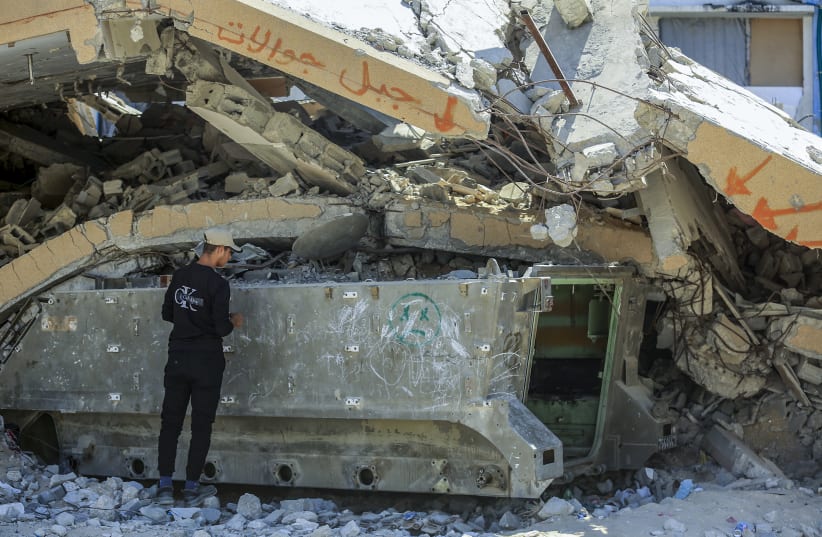 Palestinians walk past a destroyed Israeli armored vehicle left behind by the Israeli army during the recent war, in the Tel al-Hawa neighborhood of Gaza City, September 7, 2026.