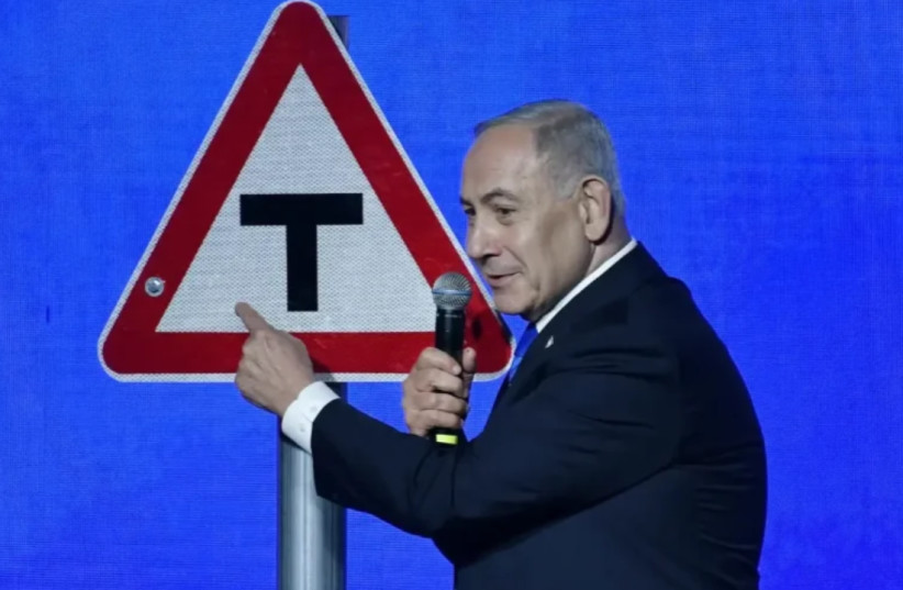 Prime Minister Benjamin Netanyahu standing on stage with a T junction traffic sign at a Likud rally in Tel Aviv, September 17, 2026.