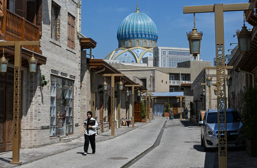A woman walks in Zarqaynar street with the Centre of Islamic Civilisation in the background in central Tashkent on April 28, 2026.