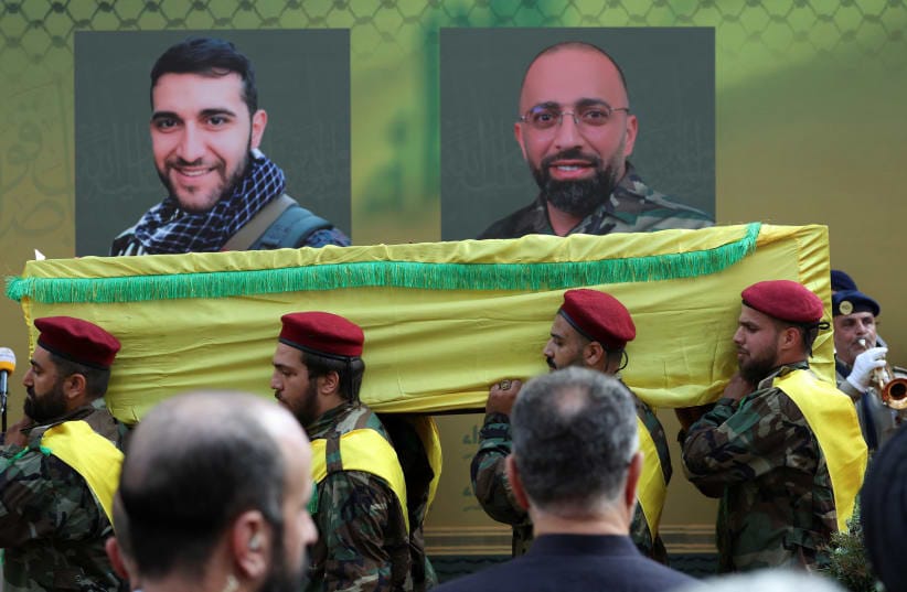 Men carry a coffin as they walk past images of Mohammad Mahdi Ammar, son of Hezbollah member of the Lebanese parliament Ali Ammar, and Abbas Fadel Yassin, who were killed amid the detonation of pagers across Lebanon, during their funeral in Beirut, Lebanon September 18, 2024.