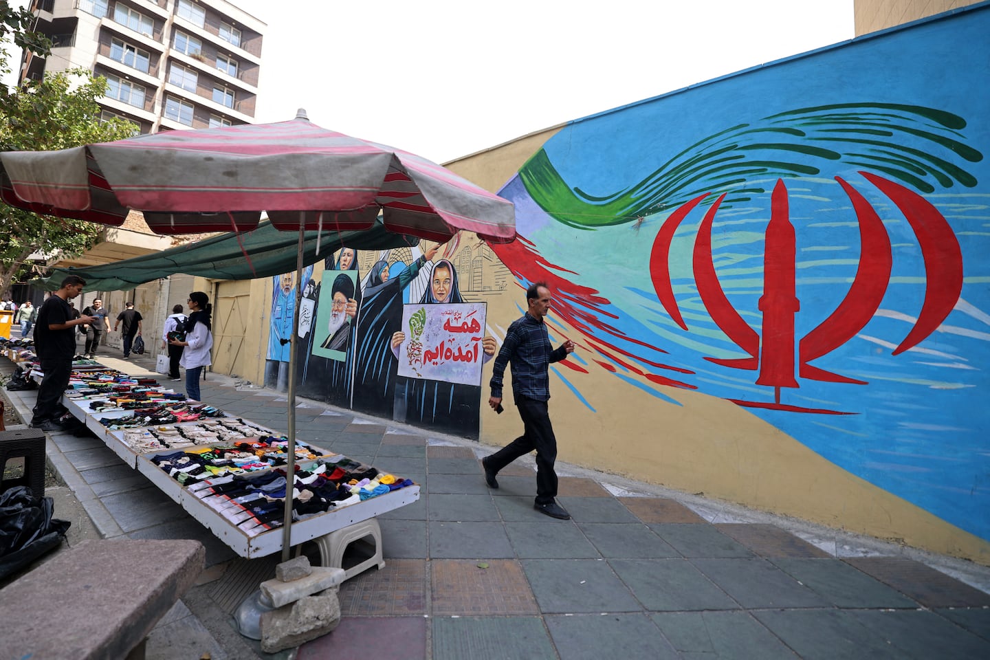 A pedestrian walks past a wall mural along a street in downtown of Tehran on Aug. 31, 2026. Iran attacked US military targets in the Middle East on Aug. 31 in retaliation for American strikes on an island in the Strait of Hormuz, the first exchange of fire for a month in a war that has engulfed the region. Six months into the conflict, the two sides remain at an impasse, with Iran keeping the strategic strait shut and Washington persisting with a naval counter-blockade of Iran.