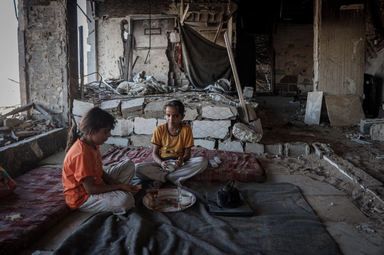 Islam’s daughters sit inside the room where they live in the Al Najma building, which is at risk of collapse.