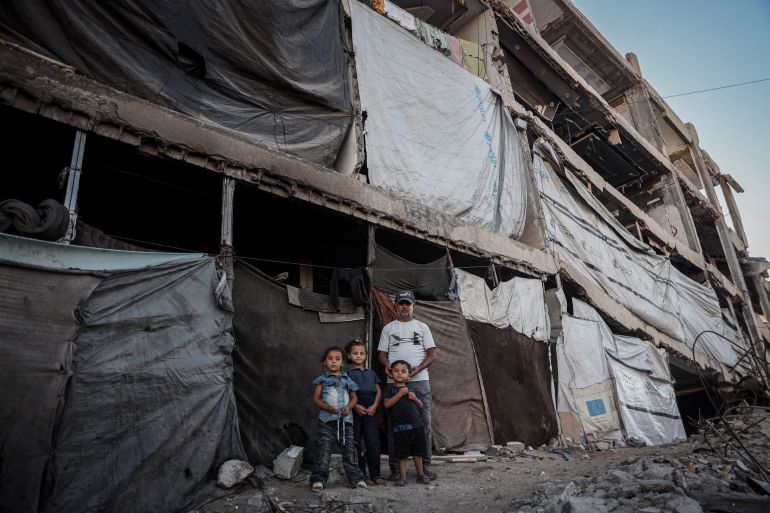 Abdullah Abu Hajar stands near the damaged building where he lives with his family