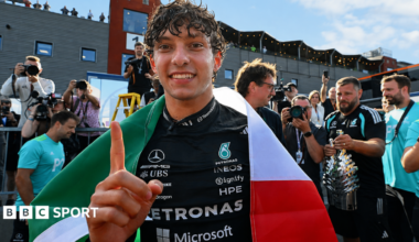 Kimi Antonelli celebrates after winning the Belgium Grand Prix, with an Italian flag draped over his shoulders