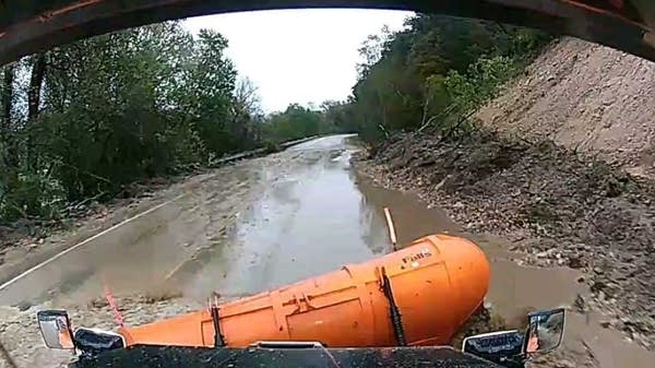 A snowplow moves through a mudslide on a highway