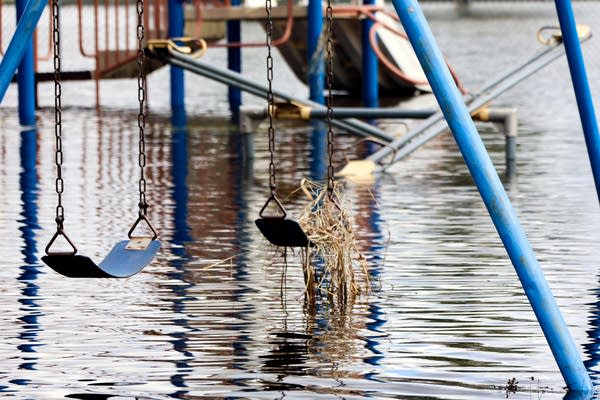 A swing set sits submerged in flood waters.