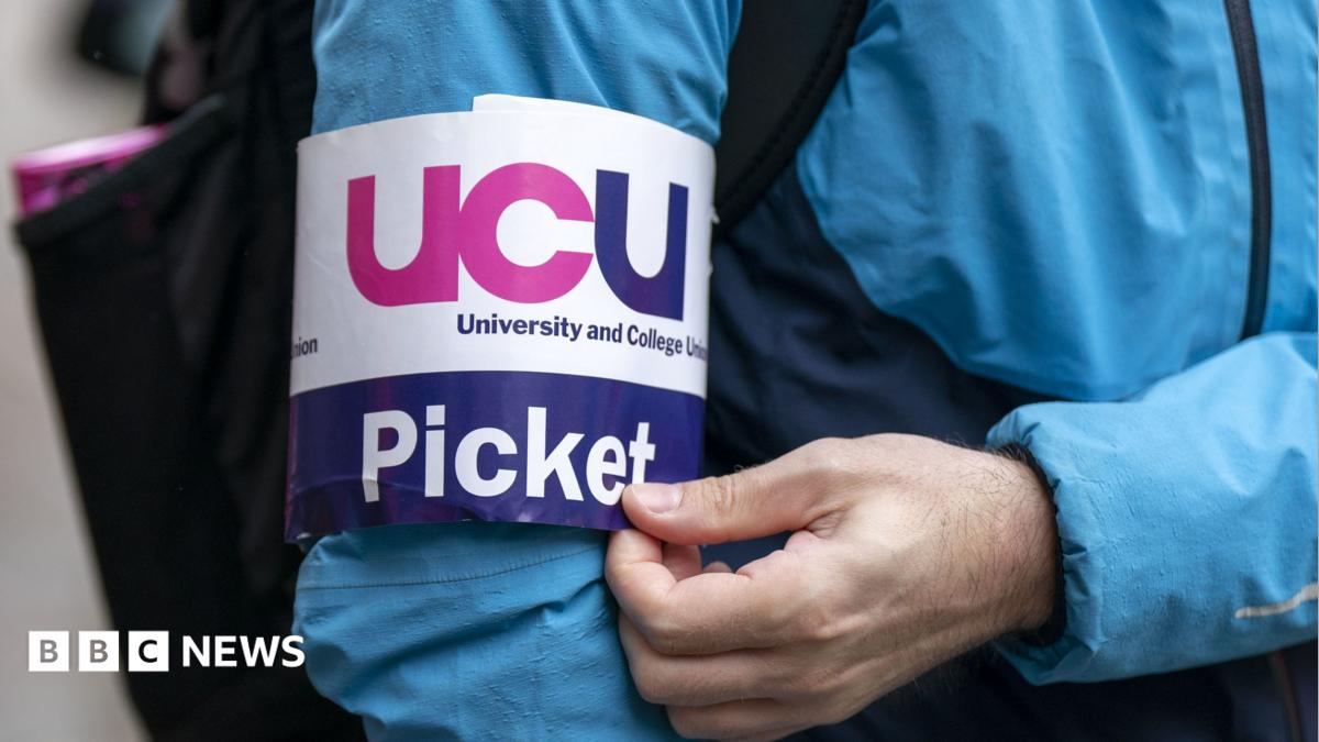 An image of a UCU picket line armband on a blue jacketed striker - the band is white with pink and navy UCU lettering.