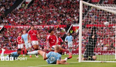 Manchester City striker Erling Haaland scores for his side as team-mate Enzo Fernandez watches on after failing to make contact with a diving header