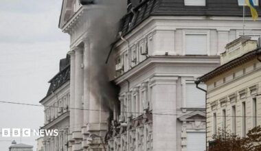 Black smoke pours from two windows in a large government building