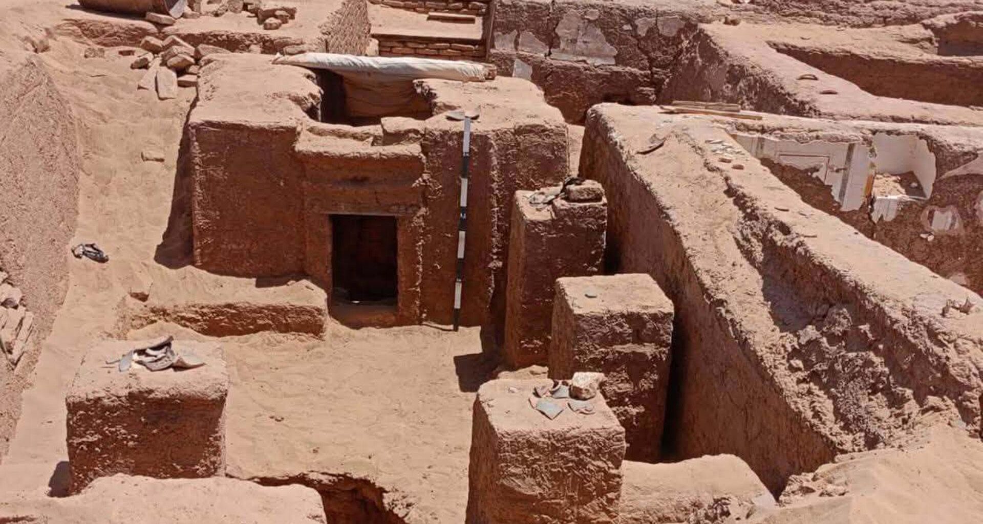 A zoomed out view of a half-unearthed tomb in the desert.