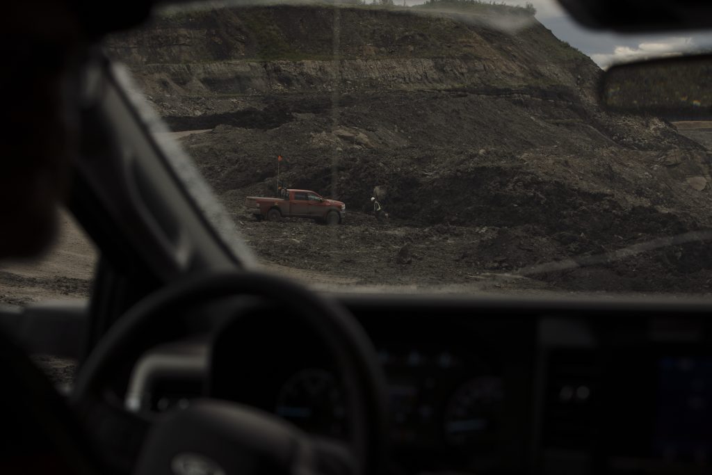 Seen through the cab of a vehicle, a worker wearing a hard hat and reflective vest walks toward his pickup truck at the Coal Valley mine south of Edson, Alberta.
