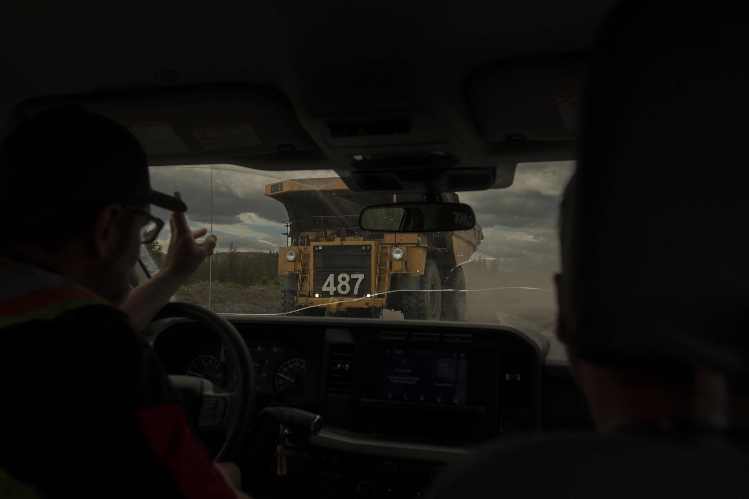 Photographed from inside the cab, a pickup truck driver waves to the driver of a massive coal dump truck at the Coal Valley mine south of Edson, Alberta.